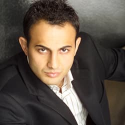 Studio headshot of Roman Mitichyan in a black suit and open-collar shirt