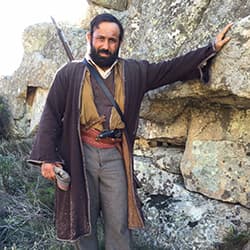 Roman Mitichyan in period costume on a rocky hillside in The Promise